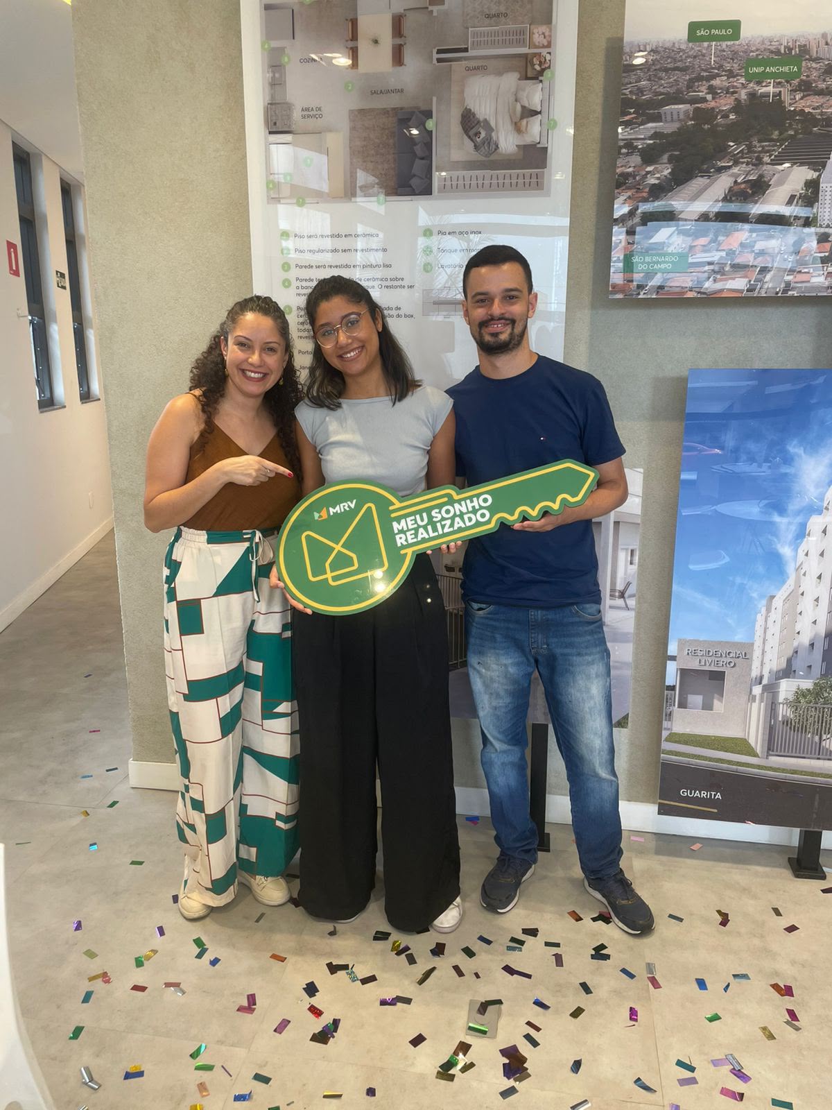 Pessoas celebrando a conquista de um imóvel com uma chave simbólica.
