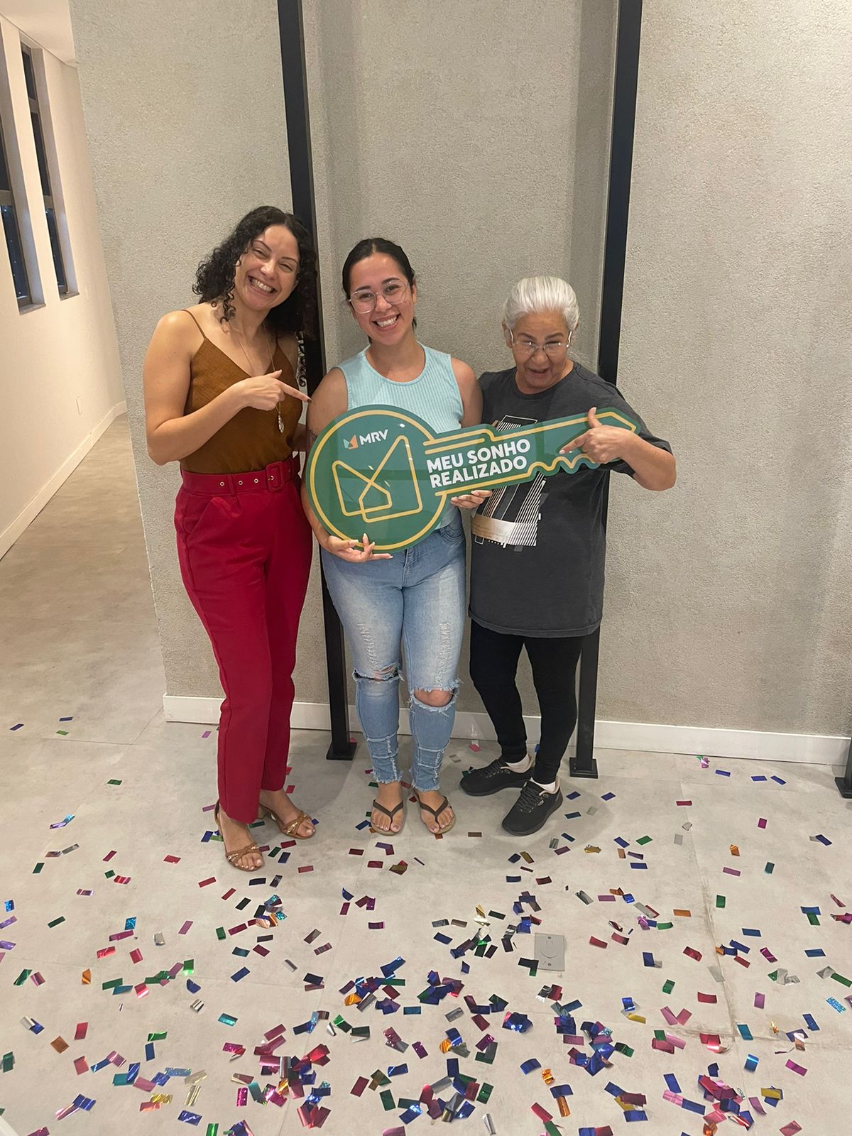 Pessoas celebrando a conquista de um imóvel com uma chave simbólica.